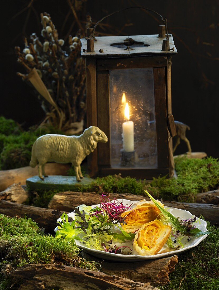 Pumpkin & marjoram strudel on winter salad, lantern in background