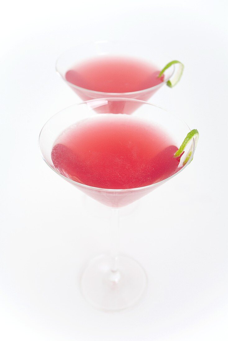 Two Cosmopolitan cocktails with lime peel