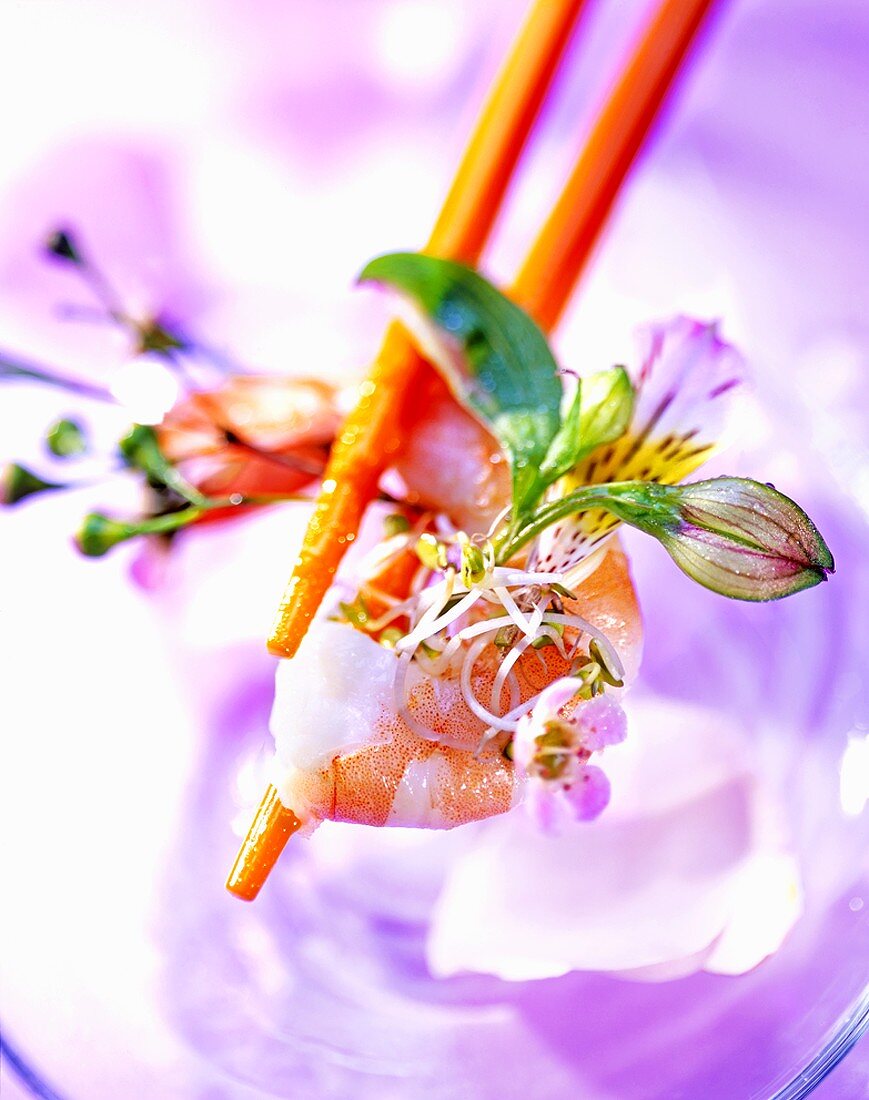 Blumensalat mit Garnele und orangefarbene Essstäbchen.