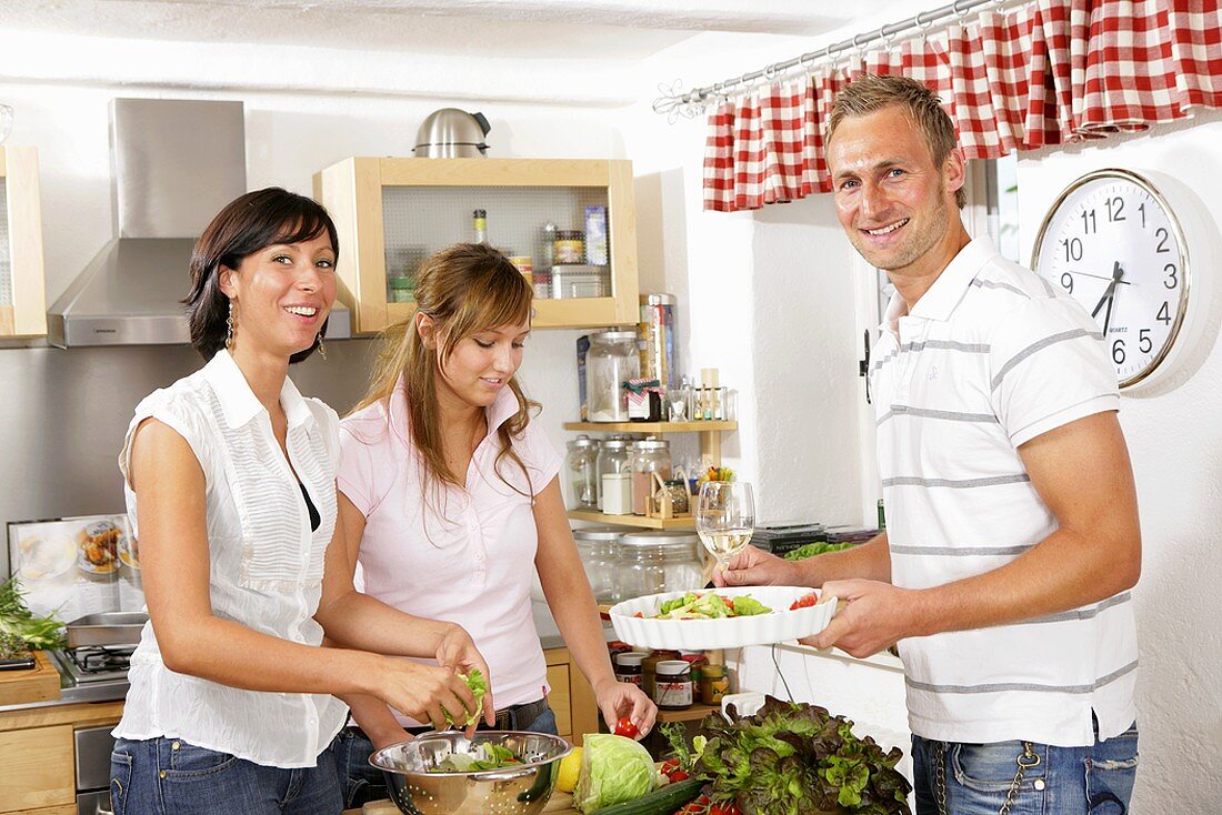 Three young people preparing salad together