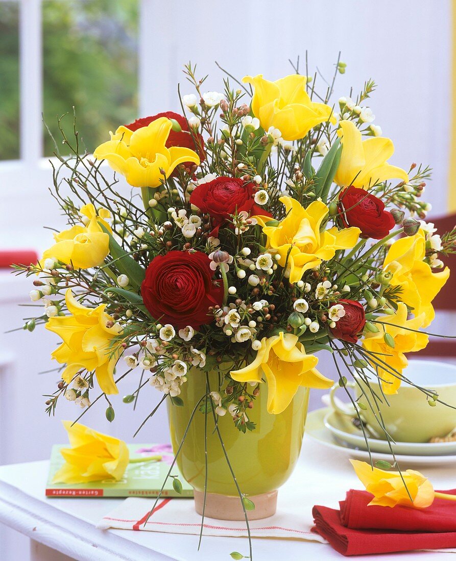 Arrangement of ranunculus, tulips, broom and wax flowers