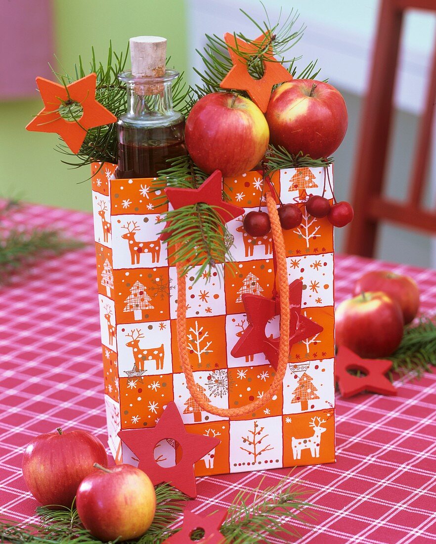 Gift bag with oil bottle, apples, Douglas fir and stars