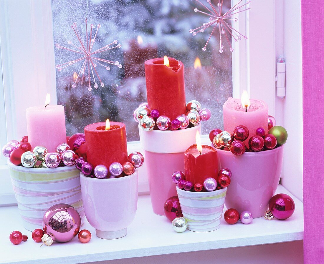 Adventliches Kerzengesteck mit kleinen Baumkugeln am Fenster
