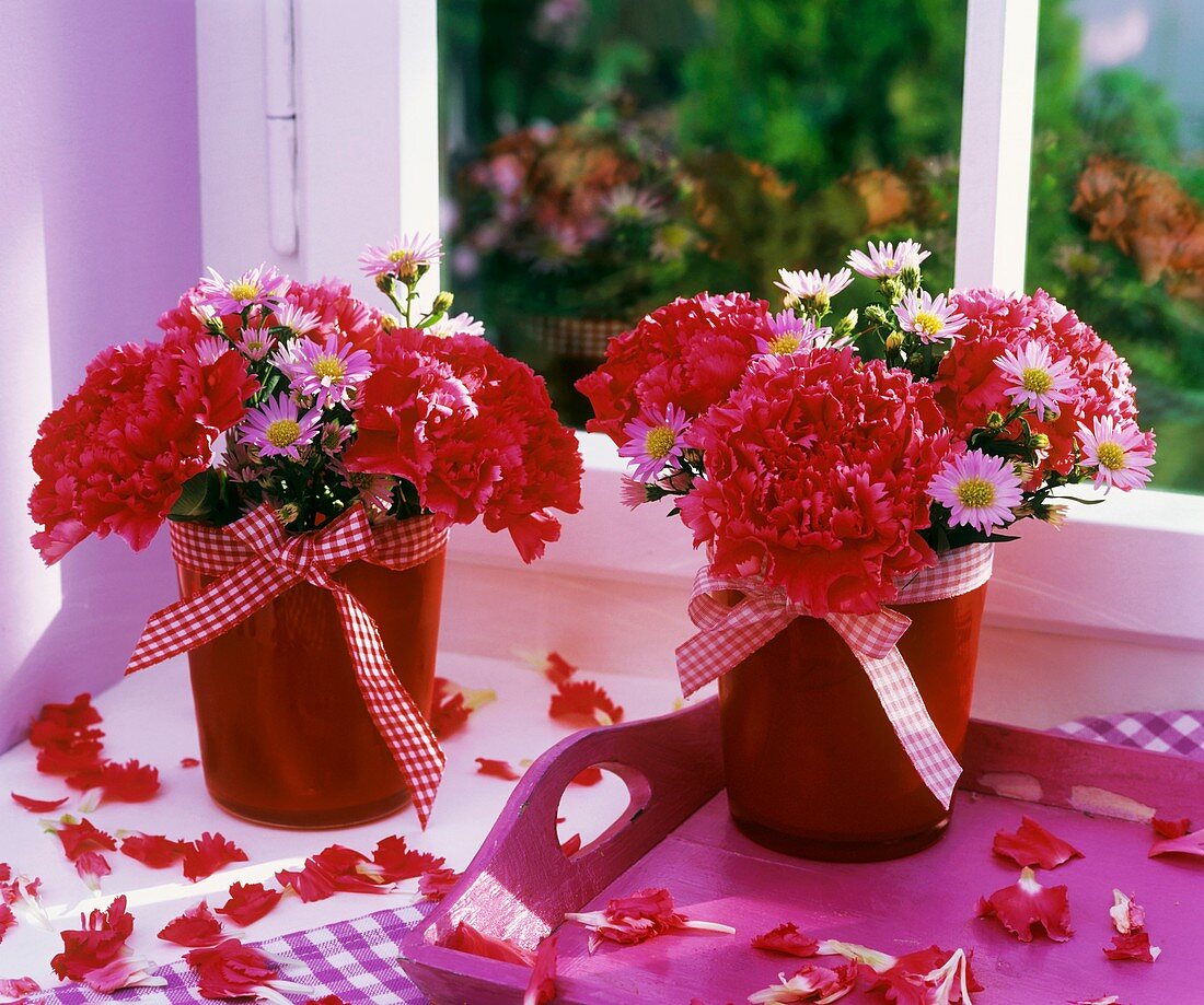 Small posies of carnations & Michaelmas daisies in red beakers