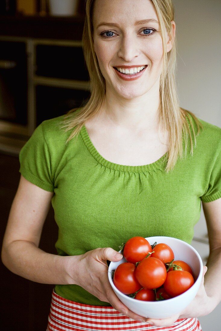 Junge Frau hält eine Schüssel mit Tomaten