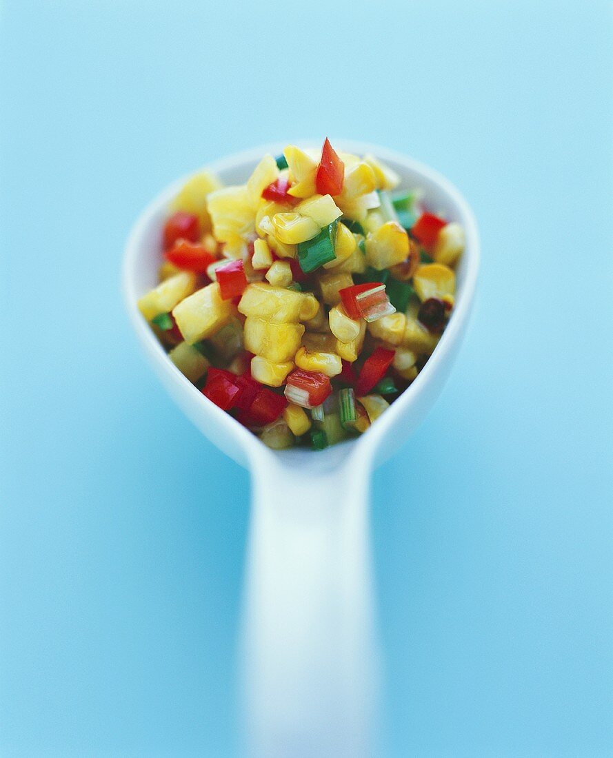 Mango salsa with sweetcorn kernels on spoon