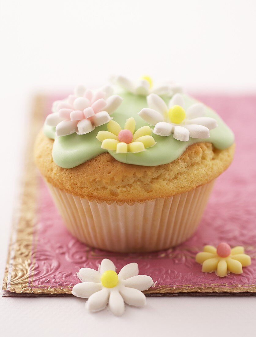 Muffin mit grünem Zuckerguss und Zuckerblüten