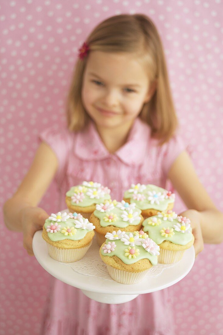 Girl holding tray of decorated muffins