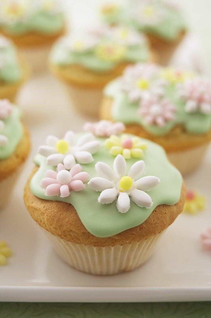 Muffins with green icing and sugar flowers (close-up)