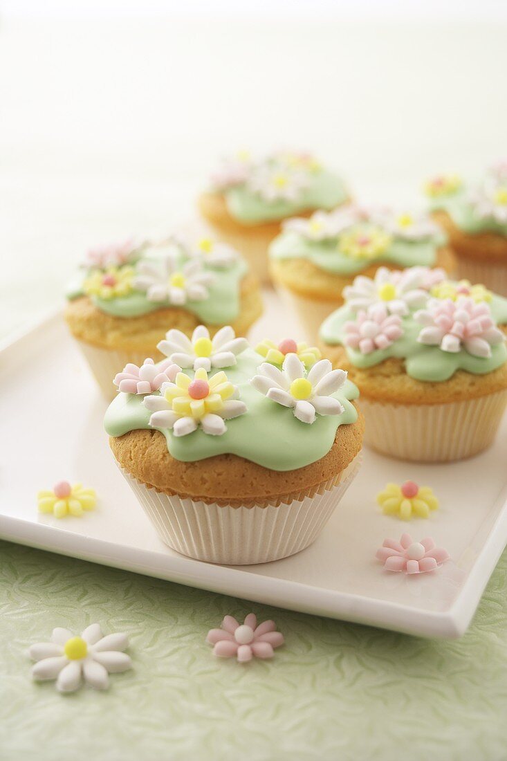 Muffins with green icing and sugar flowers on tray