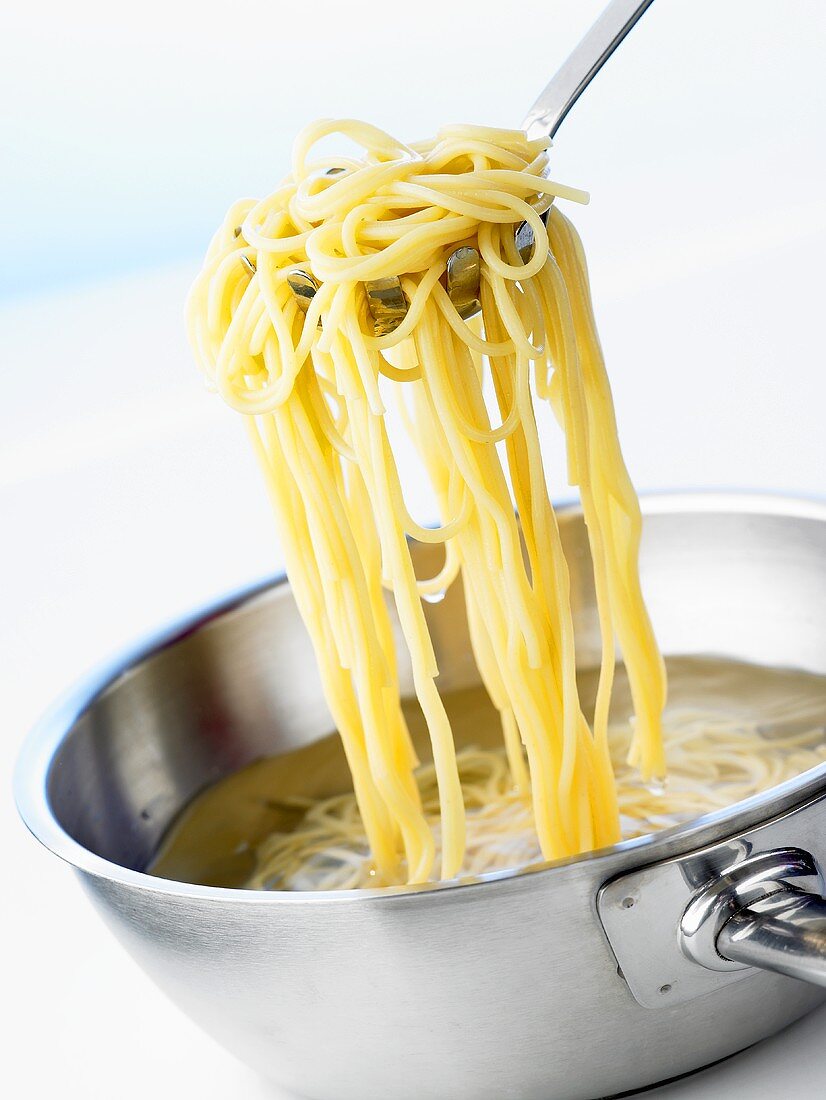 Spaghetti mit Spaghettiheber aus dem Wasser nehmen