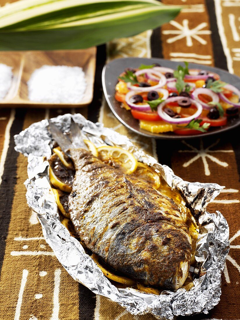 Fish with lemon slices cooked in aluminium foil