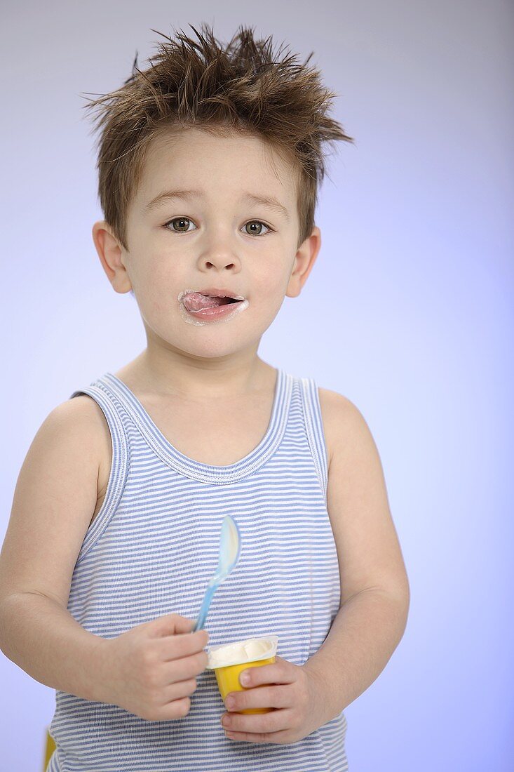 Kleiner Junge mit Joghurt in der Hand