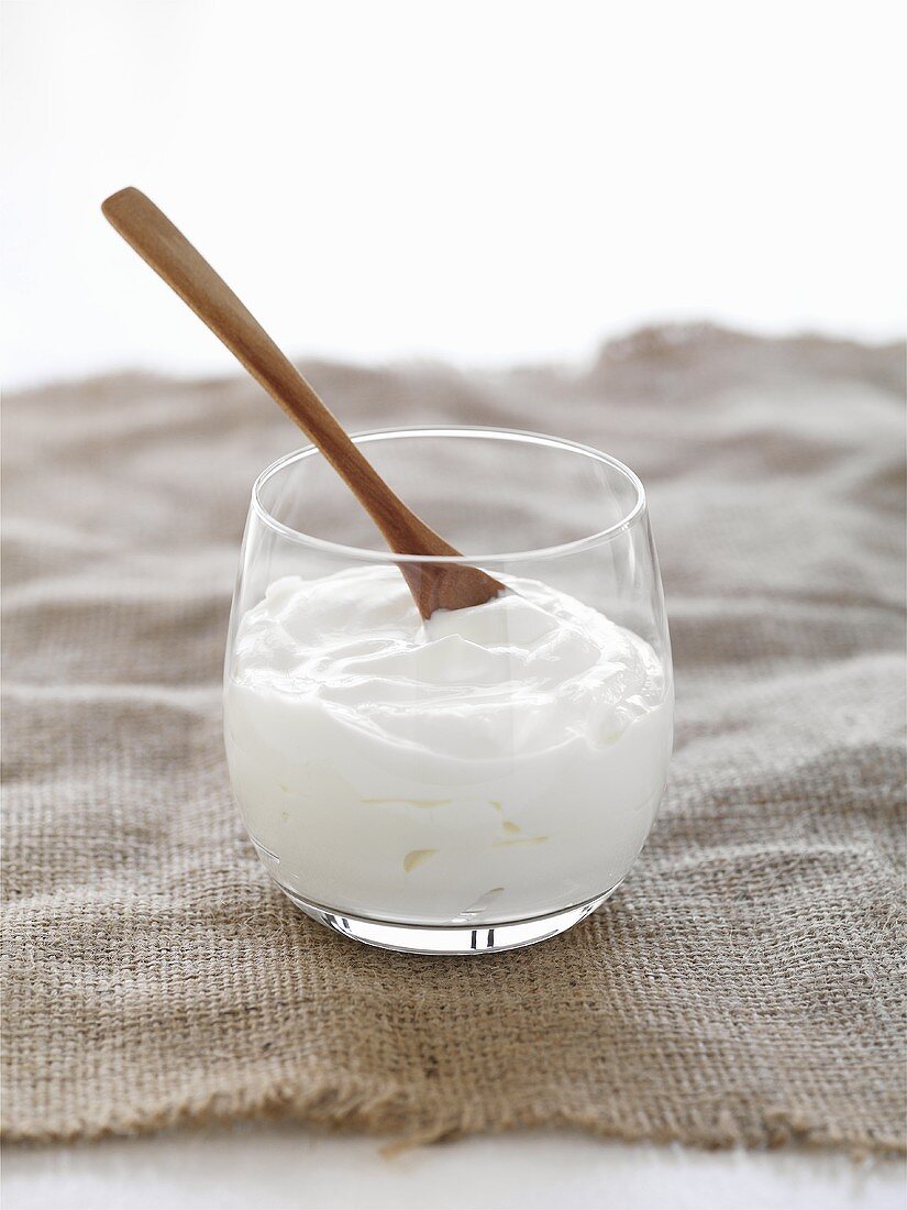 Yoghurt in glass with wooden spoon