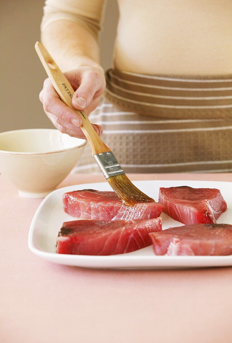 Brushing tuna fillets with oil