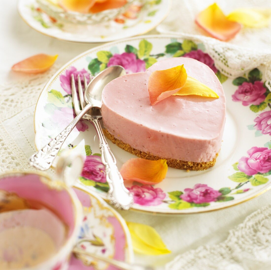 Herzförmiger rosa Käsekuchen mit Rosenblütenblättern