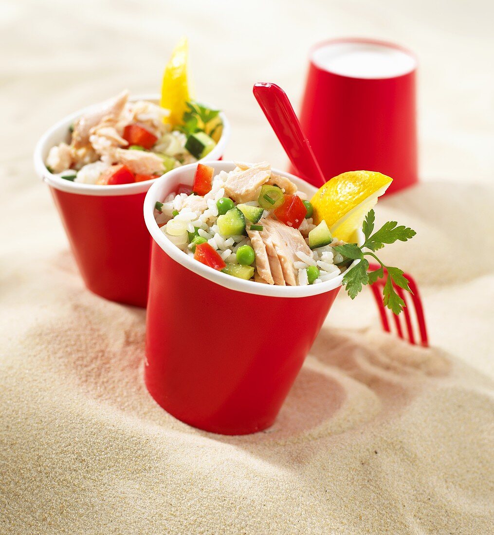 Rice salad with salmon and vegetables in red paper cups