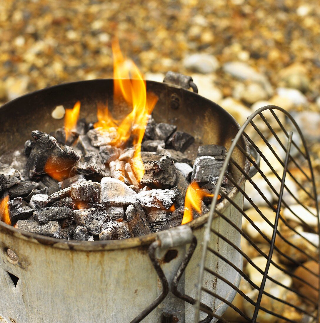 Brennende Holzkohle im rostigem Topf