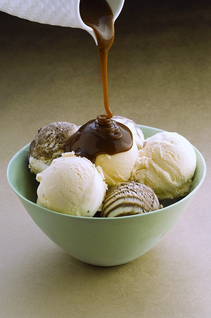 Pouring chocolate sauce over mixed ice cream