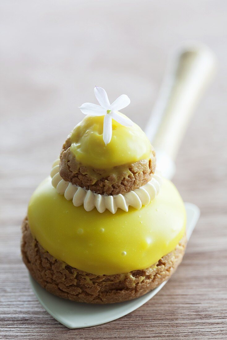 Törtchen mit Zuckerguss und Jasminblüte auf Schaufel