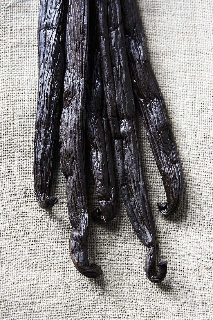 Several vanilla pods on linen cloth