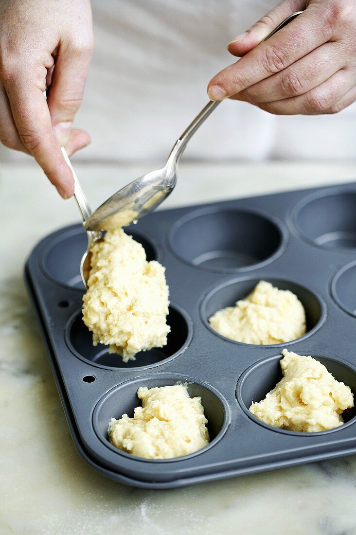 Putting muffin mixture into muffin tin