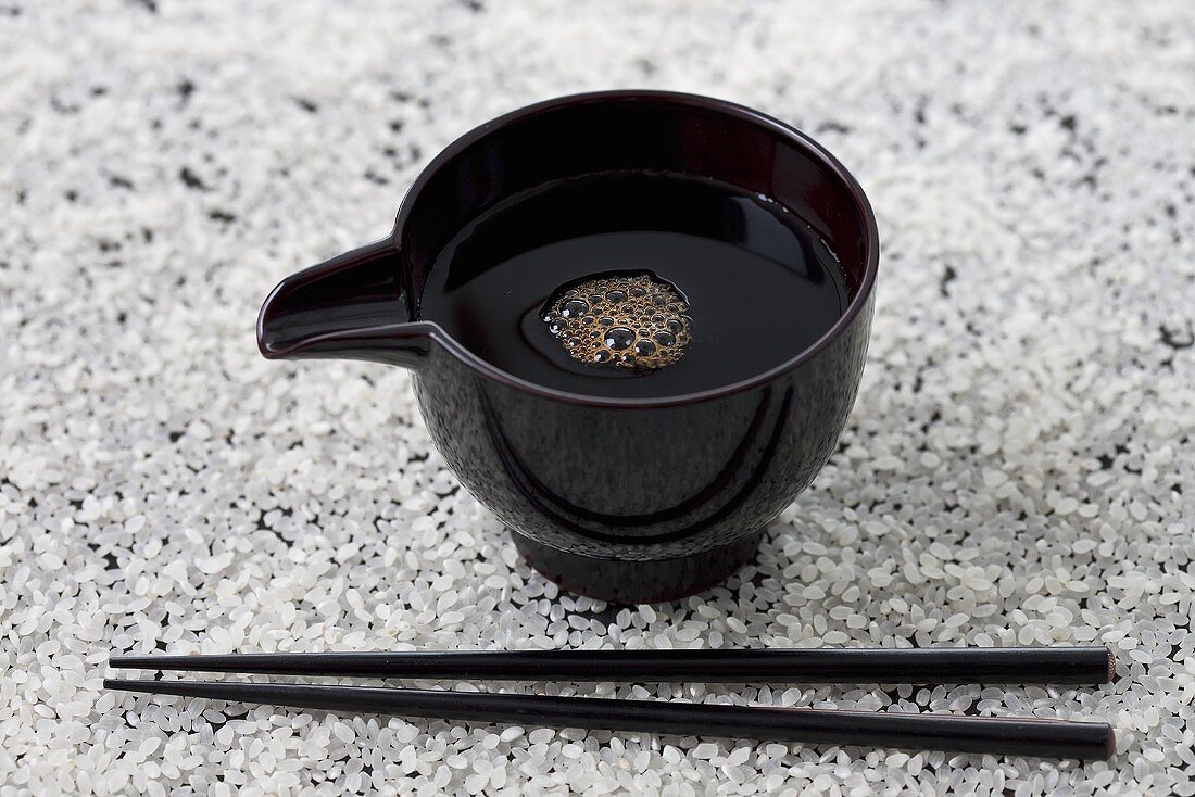 Small bowl of soy sauce and chopsticks on rice