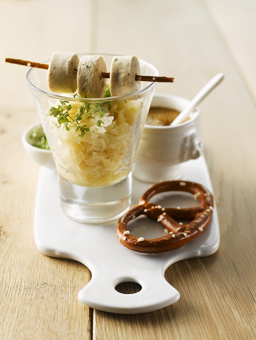 Sauerkraut im Glas mit Weißwurstscheiben und Salzbrezel