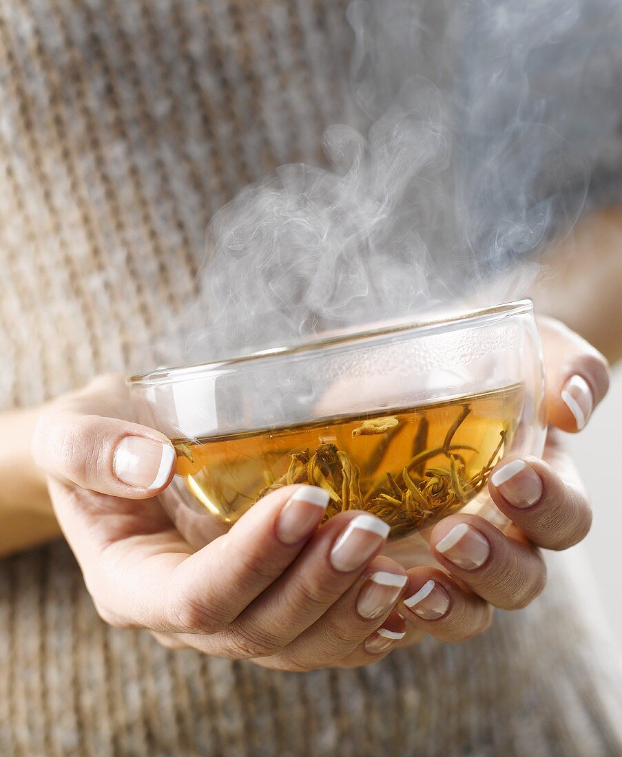 Woman holding a steaming cup of jasmine tea in her hands