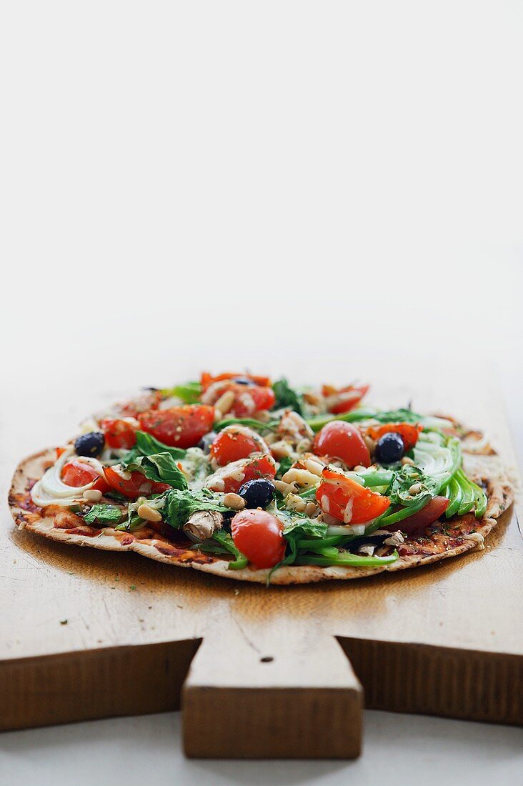 Vegetable pizza with tomatoes and olives on chopping board