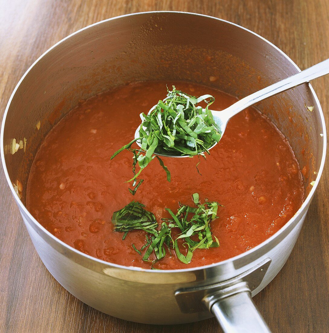 Mixing tomato sauce with basil