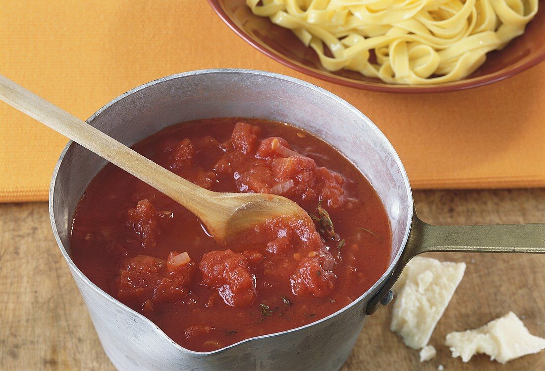 Tomato sauce in pan with wooden spoon