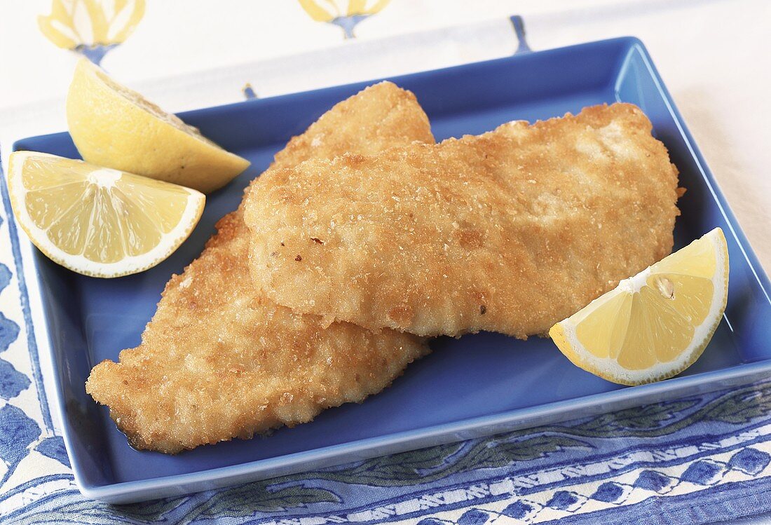 Breaded fish fillets with lemon wedges