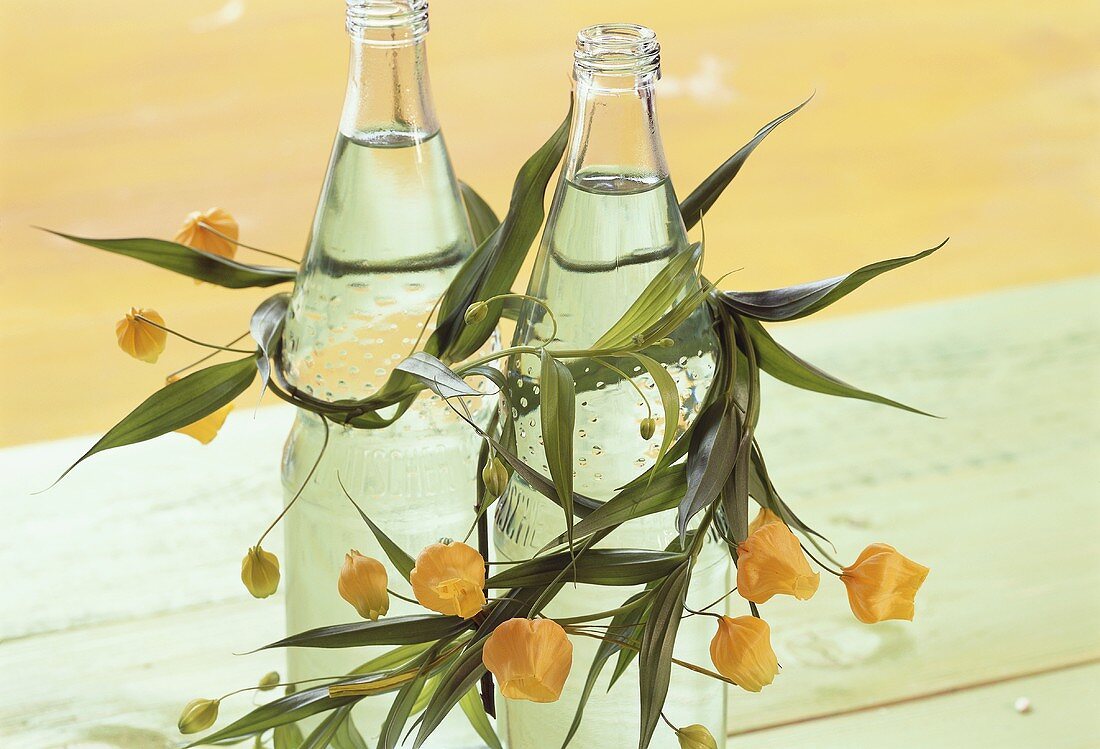 Summer table decoration: bottles of water with flower garland