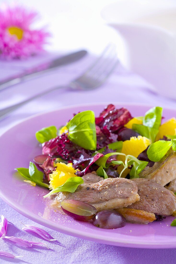Duck breast with salad leaves, orange segments and grapes