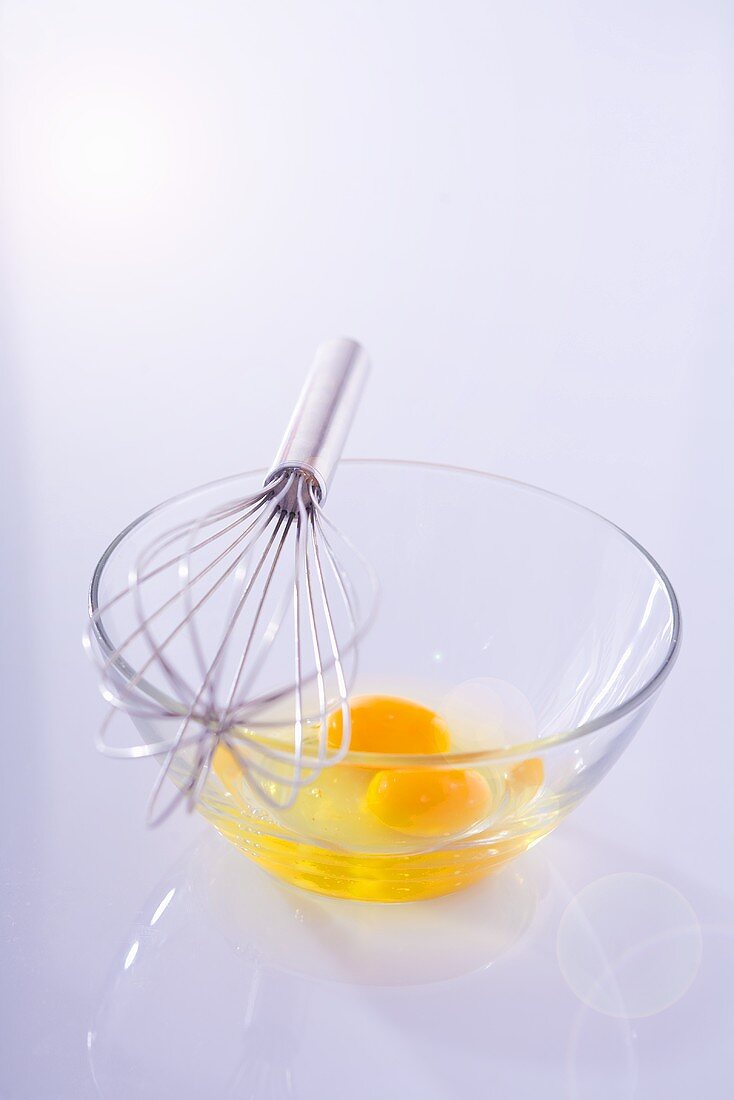 Egg yolks in glass bowl with whisk
