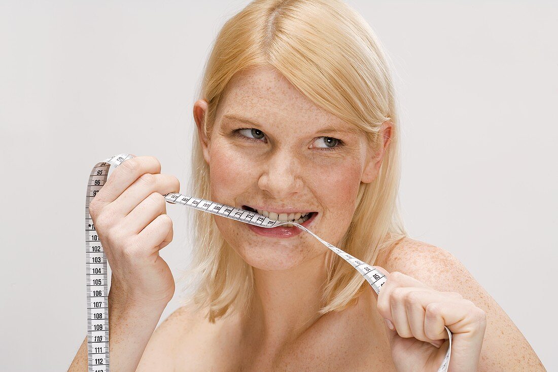 Blond woman biting tape measure