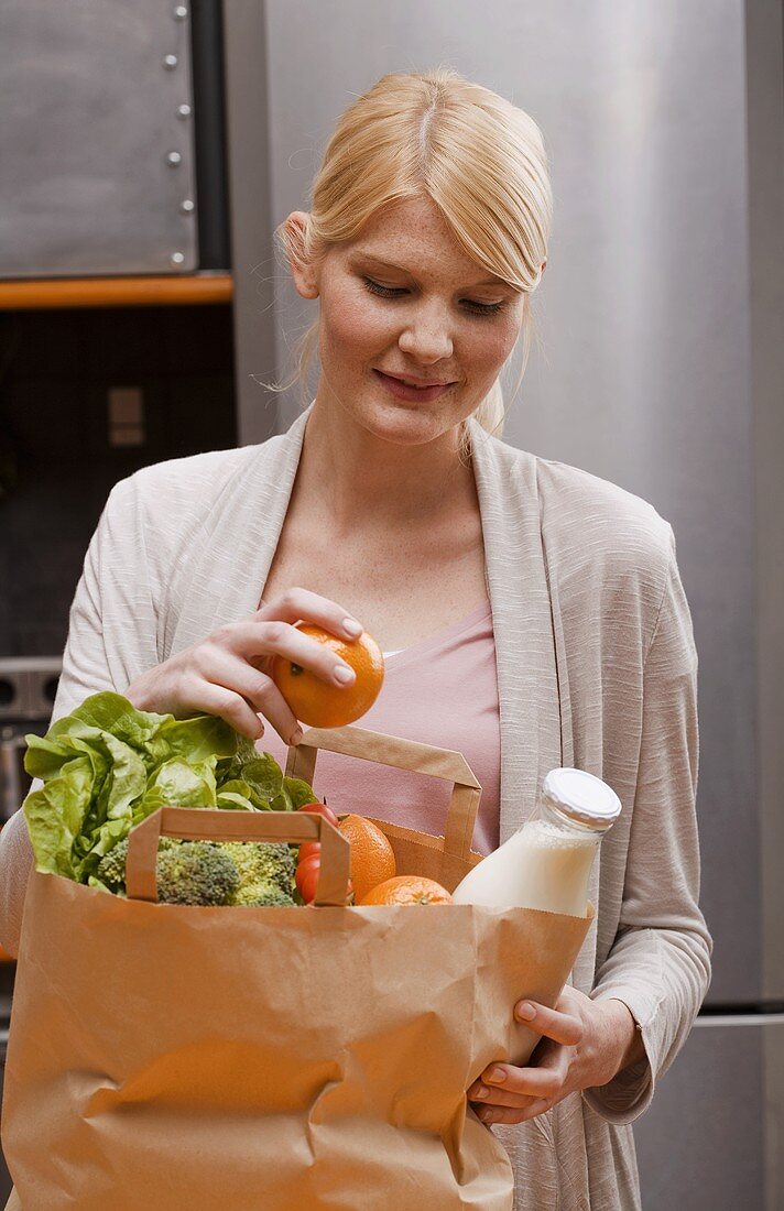Blond woman with bag of shopping in kitchen