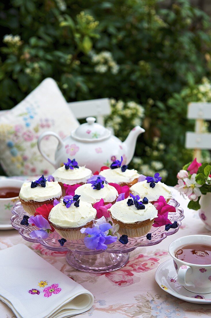 Cupcakes mit Veilchen auf Tortenständer, Tee