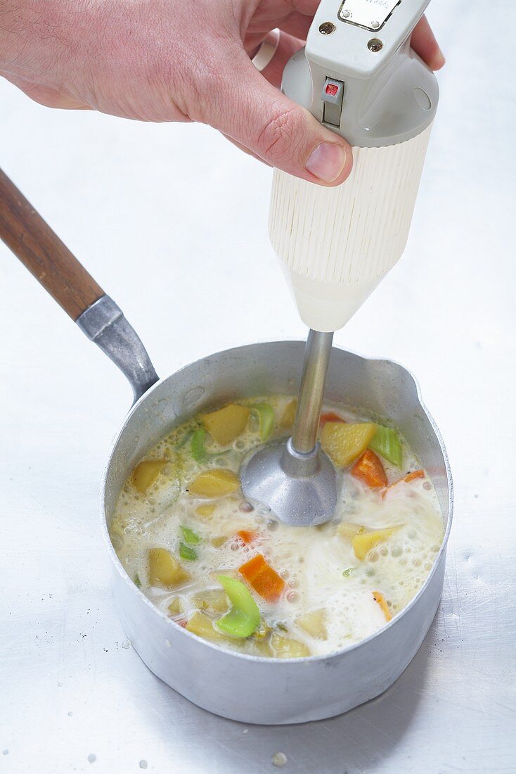 https://media02.stockfood.com/largepreviews/ODg3MzI4NQ==/00286235-Pureeing-vegetable-soup-with-a-hand-blender.jpg