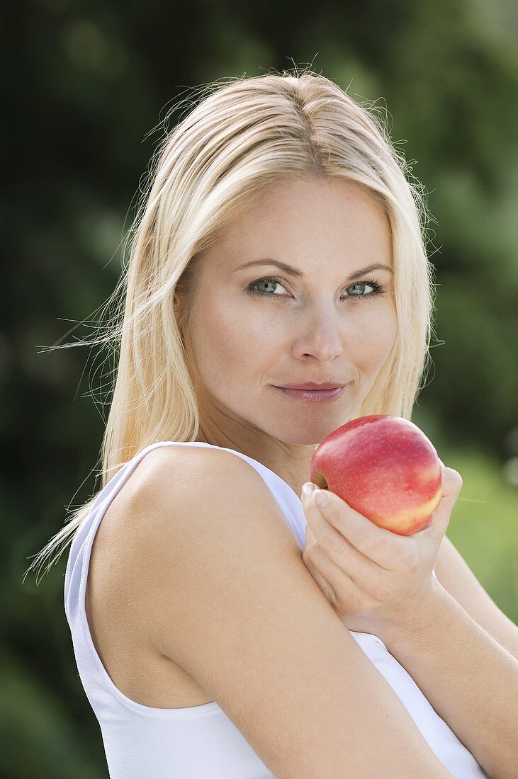 Blonde Frau hält Apfel