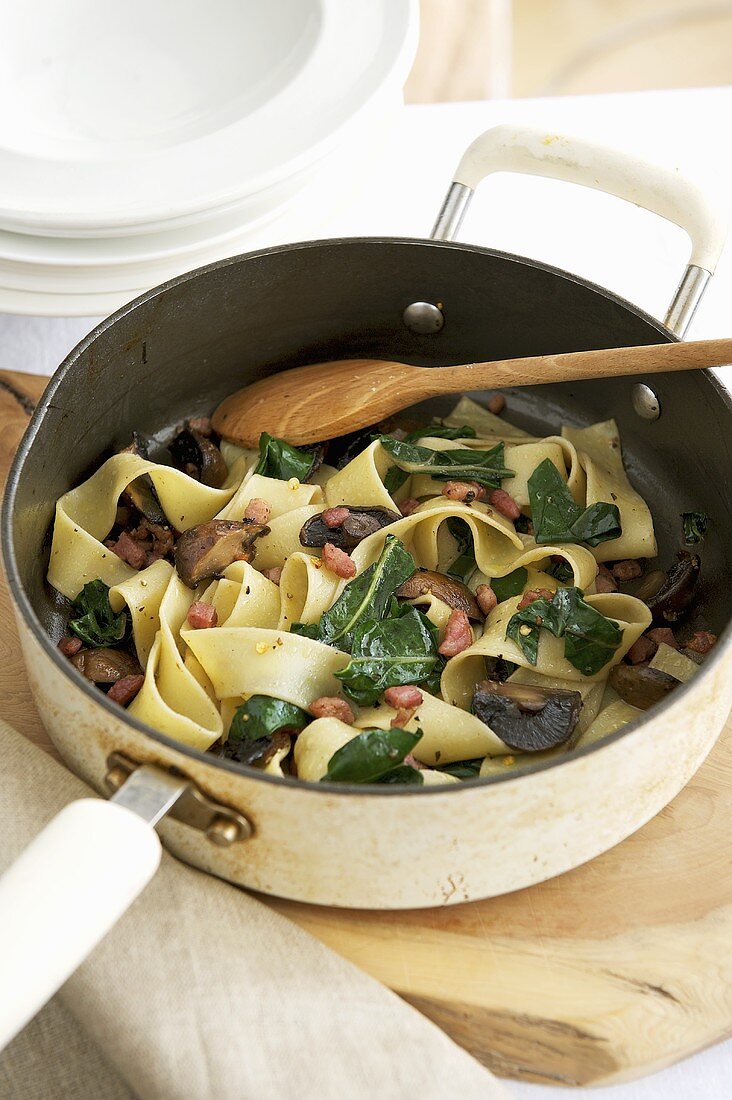 Fettuccine with ceps, bacon and spinach in pan