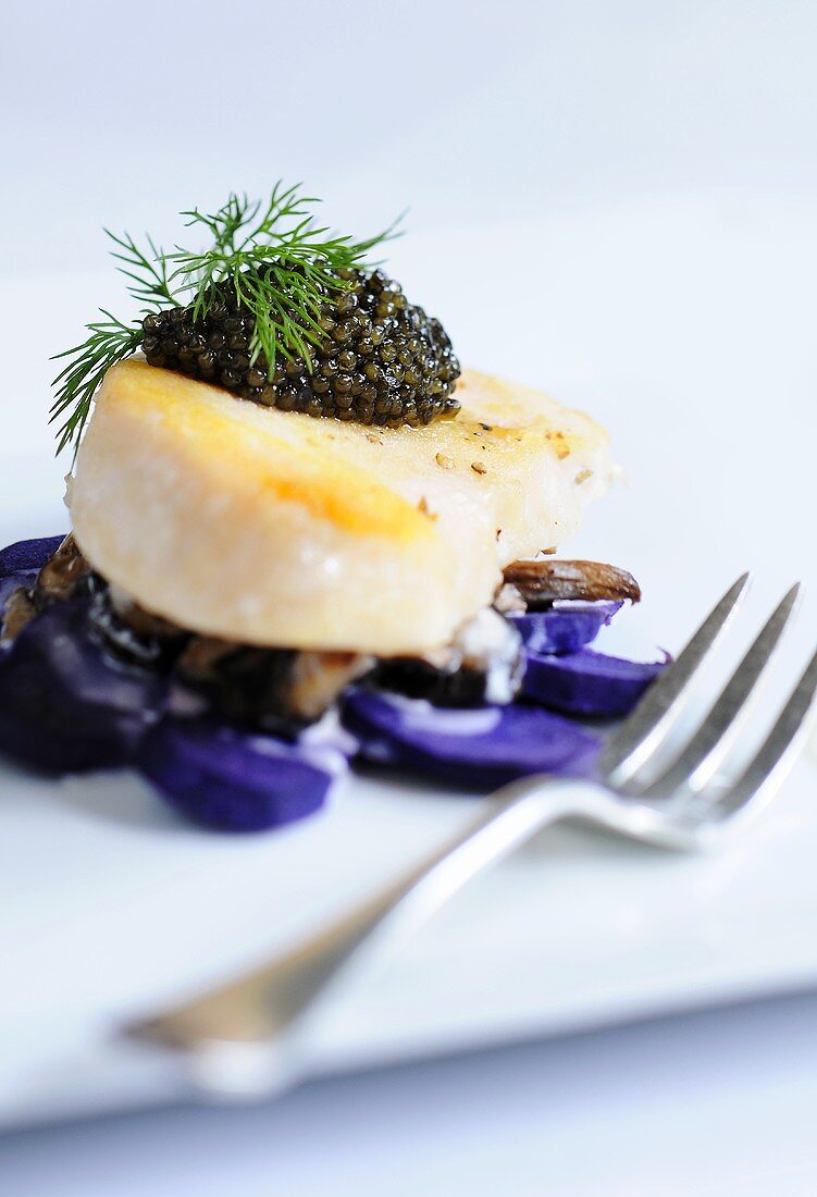 Jakobsmuschel mit schwarzem Kaviar auf violetten Kartoffeln