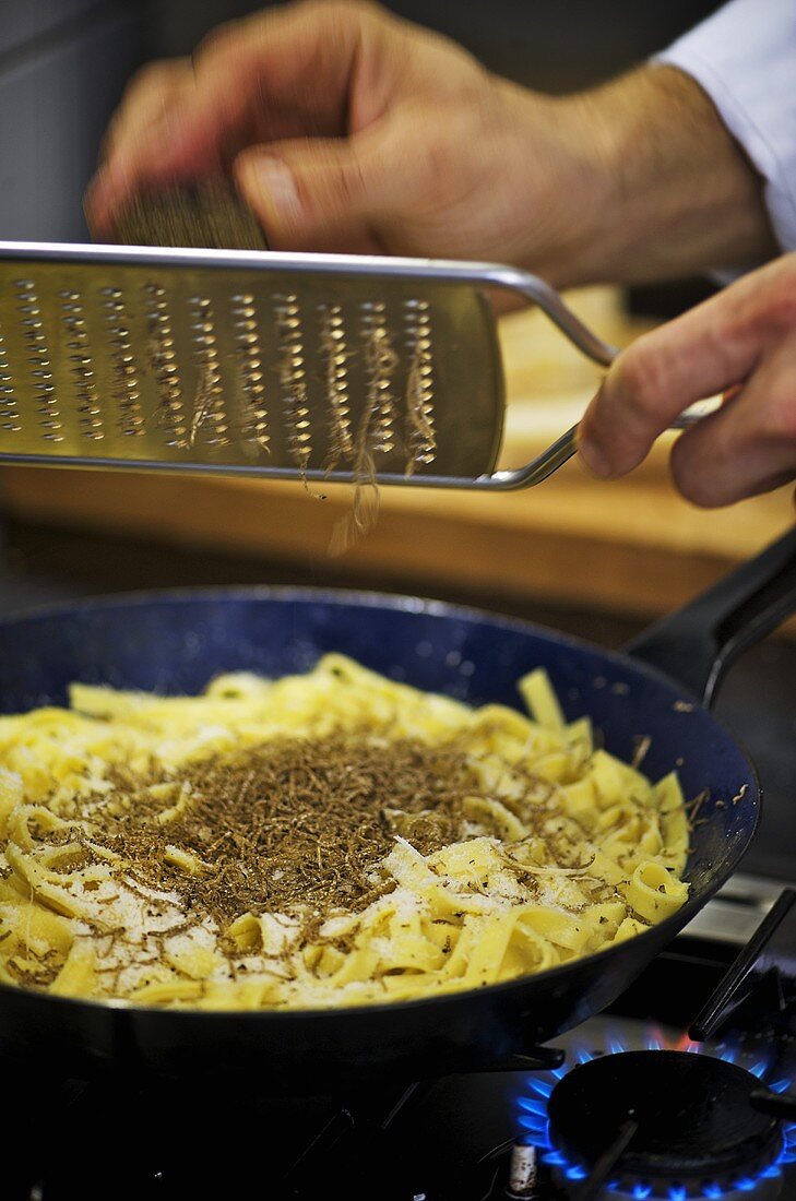 Grating truffle over ribbon pasta