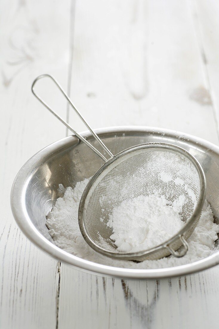 Icing sugar in dish and sieve
