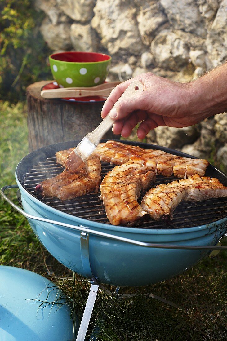 Bauchfleisch vom Schwein auf dem Grill einpinseln