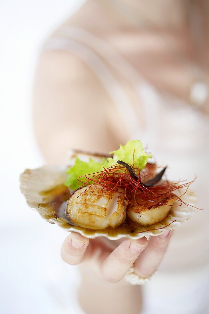 A woman holding grilled scallops