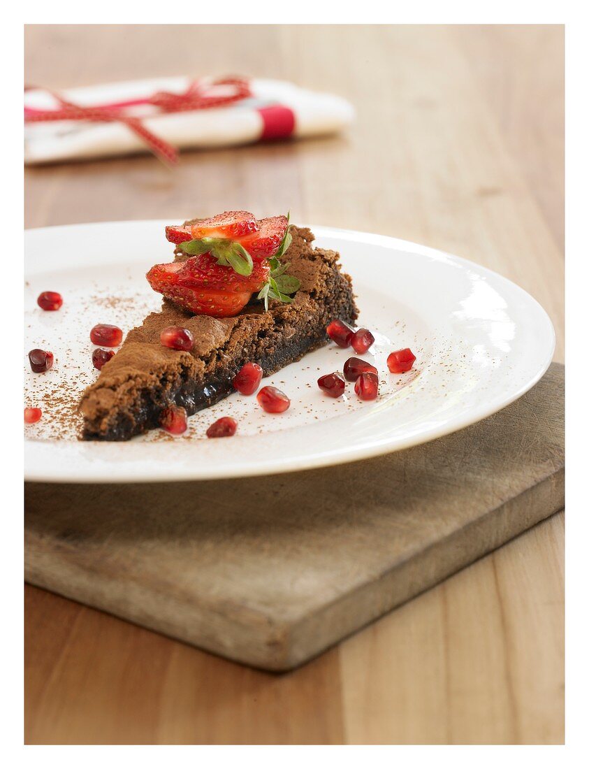 Piece of polenta chocolate cake with strawberries & pomegranate seeds