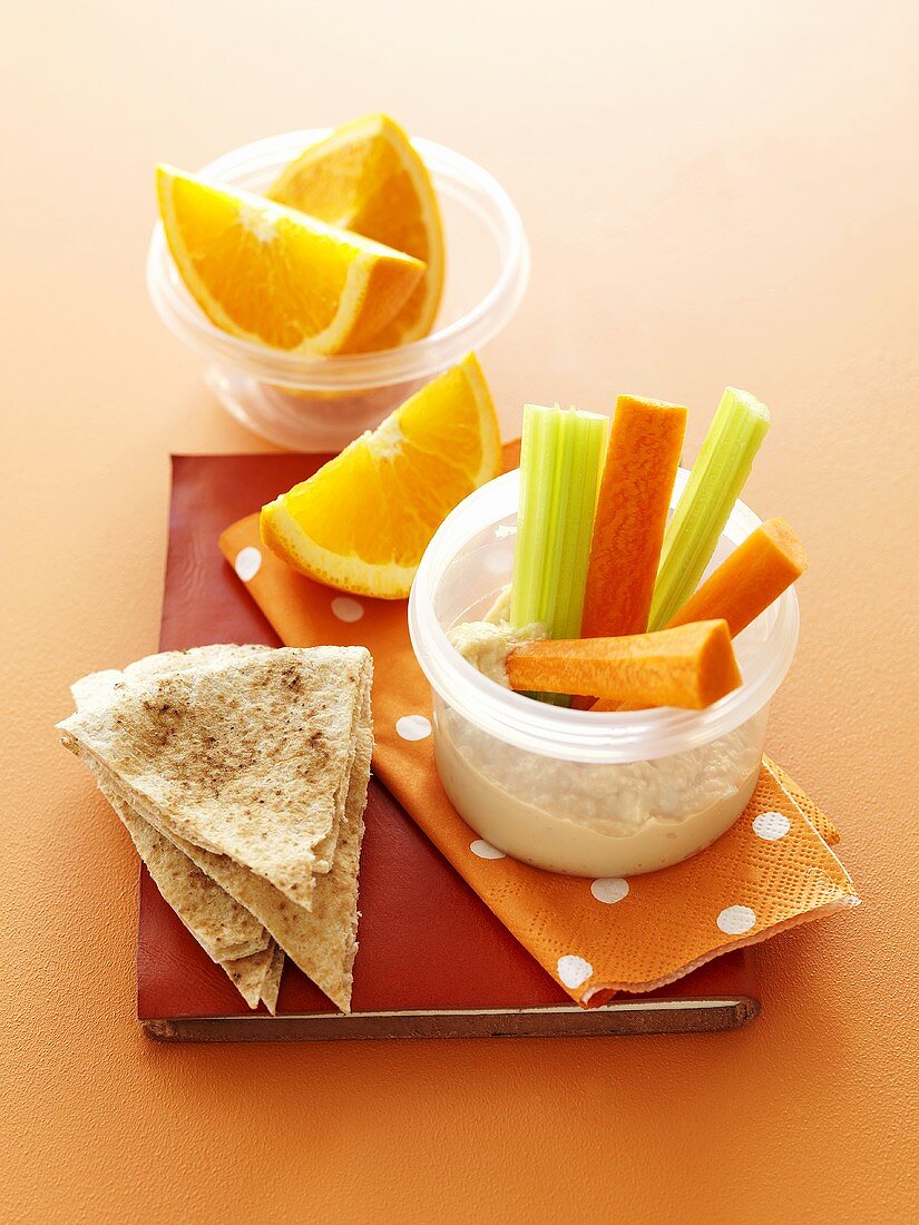 Hummus with vegetable sticks, pita bread and orange wedges for lunch