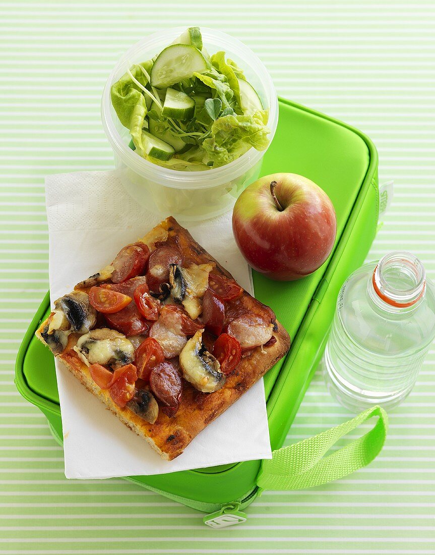 Pizza, Apfel und Salat auf Lunchbox